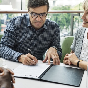 a man carefully signing a deal