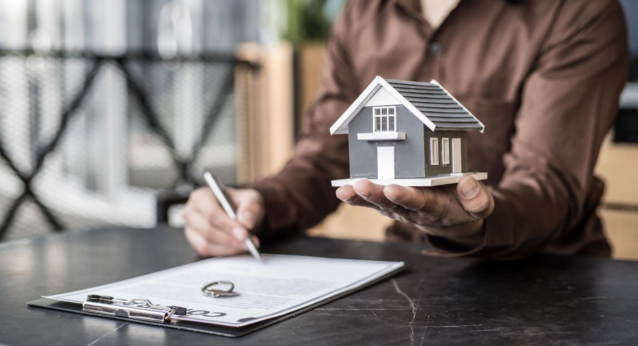 a miniature house held on the palm of the person